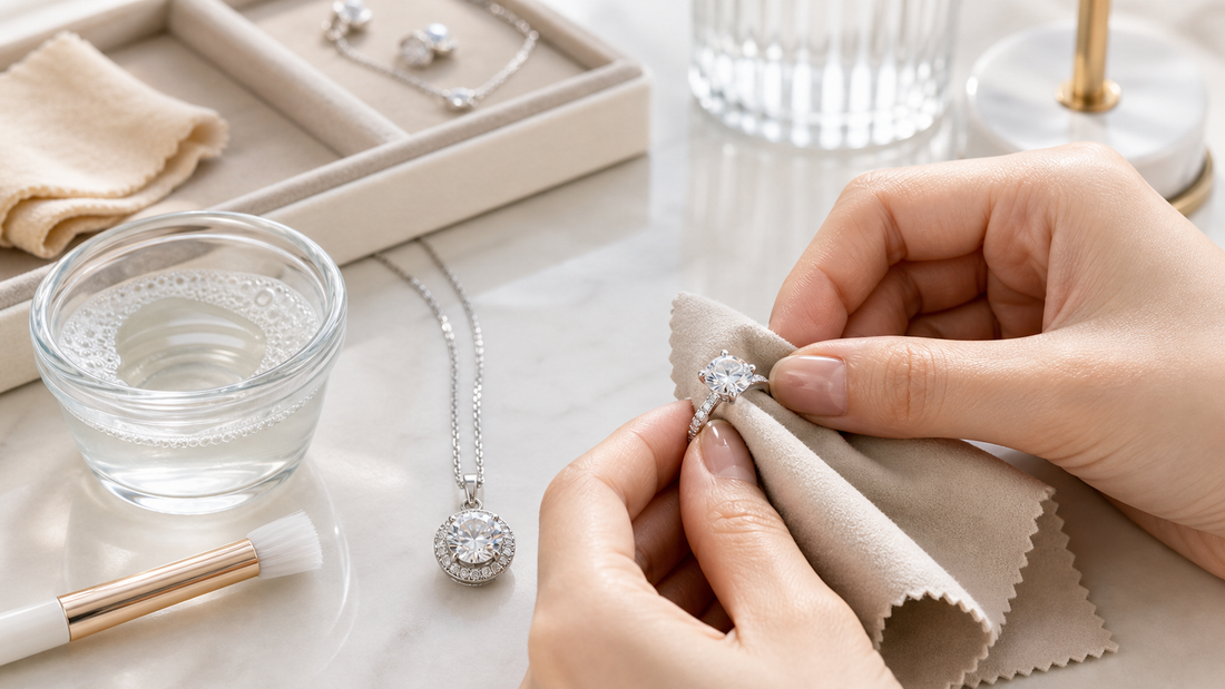 Close-up of hands gently cleaning a moissanite ring and pendant with a soft jewelry cloth on a bright vanity table.