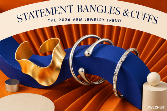 Gold and silver statement bangles arranged around a cobalt sculptural form with warm orange fabric and JWLZHUB branding.